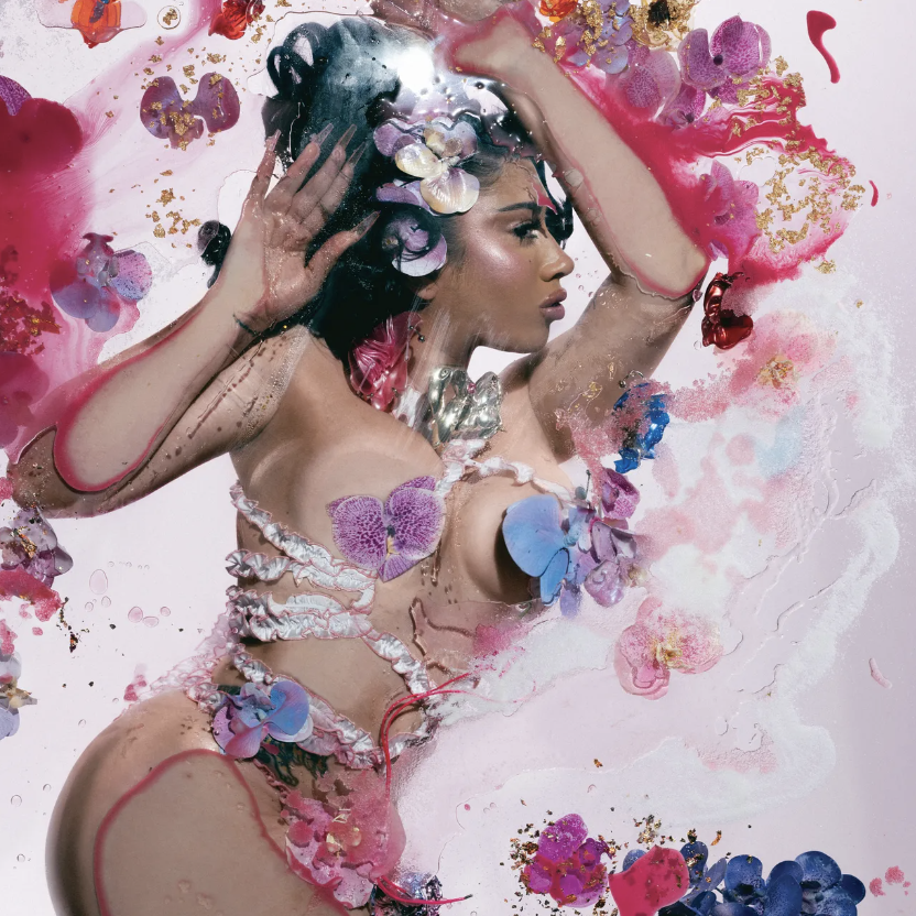 The “Orquídeas” album cover portrays Grammy-winning musician Kali Uchis submerged in water, covered in orchid petals and surrounded by vibrant cool tones.
